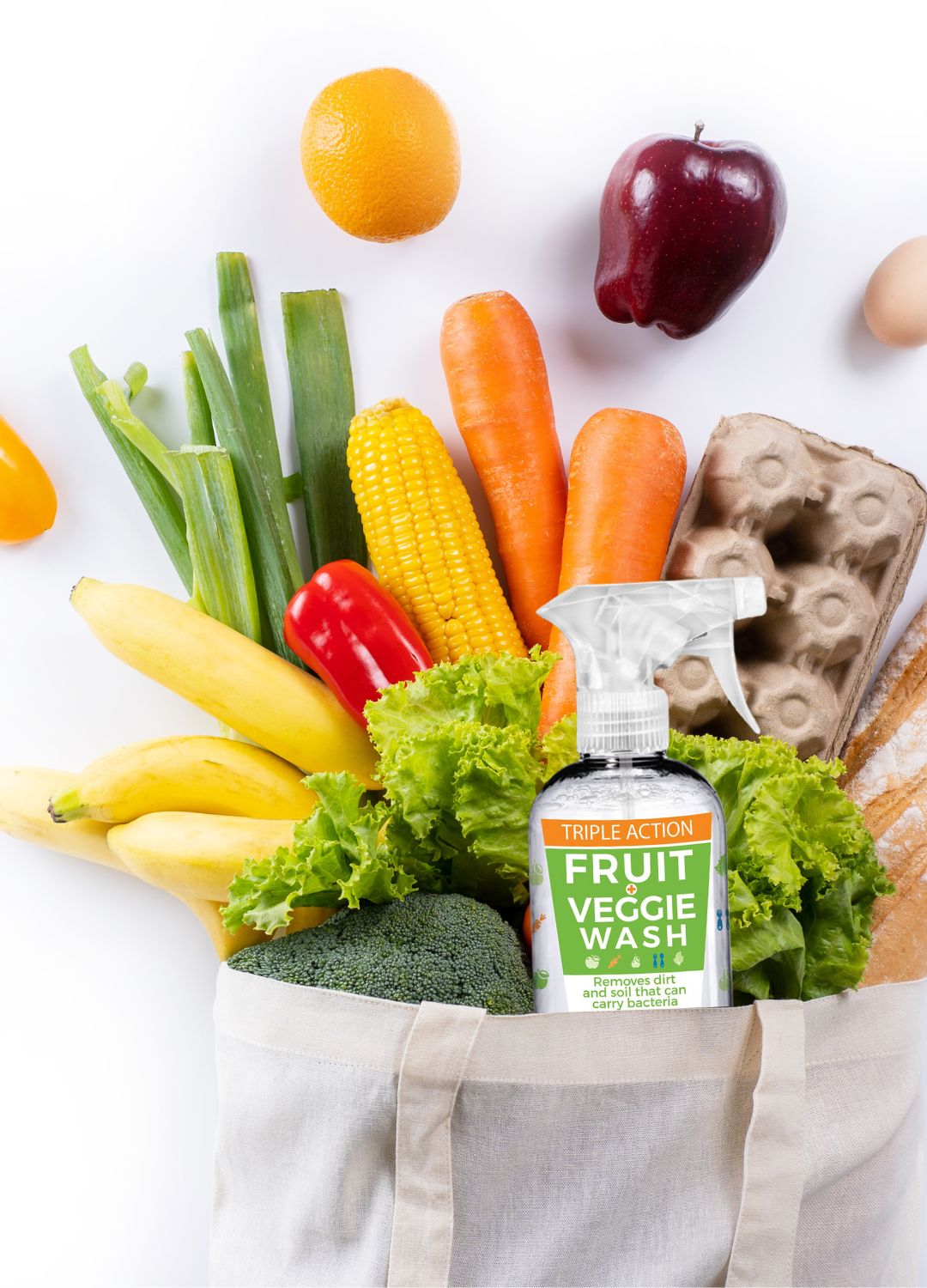 A canvas tote of vegetables and fruit with a bottle of produce wash